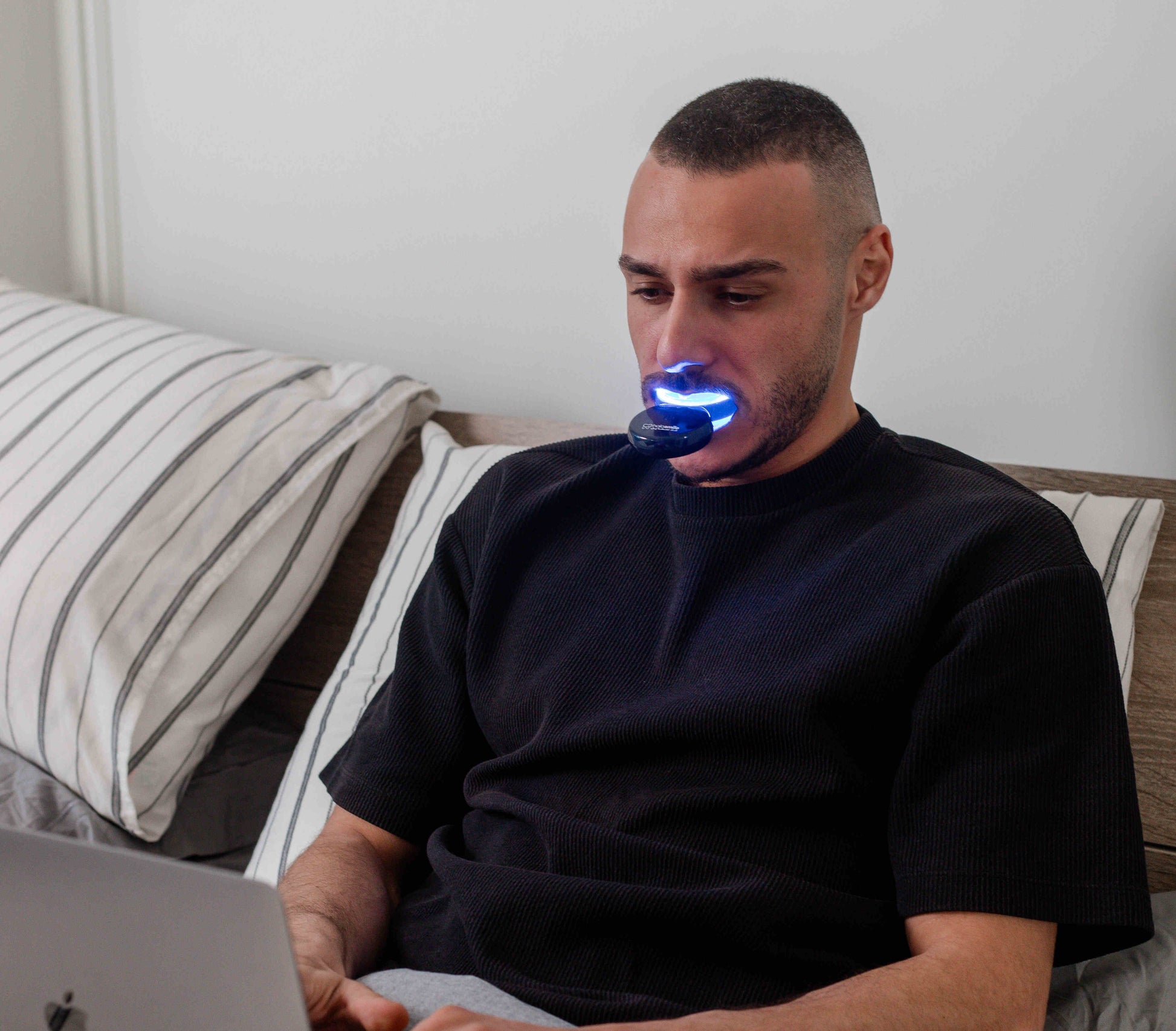 image of man using teeth whitening device while working